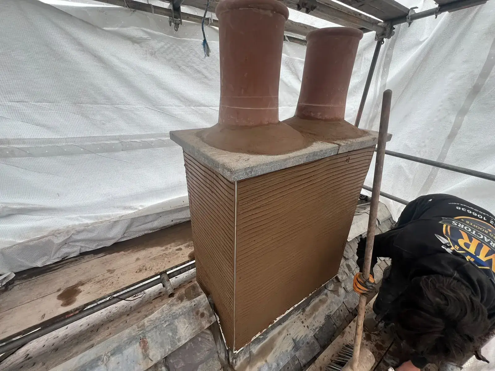 Alexander, founder of AGM Roofing, re-rendering a chimney stack from the scaffold