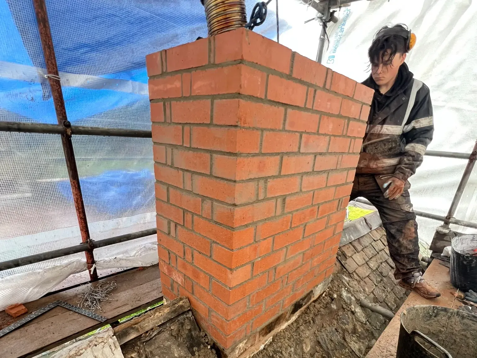AGM Roofing rebuilding a chimney stack in new brick from the scaffold