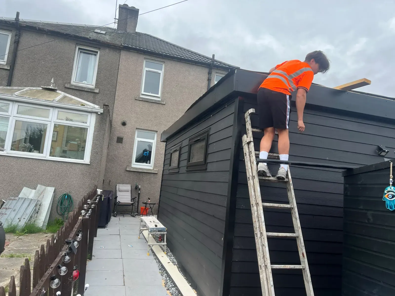 Roofer fitting the flat roof edge trim on a garden room