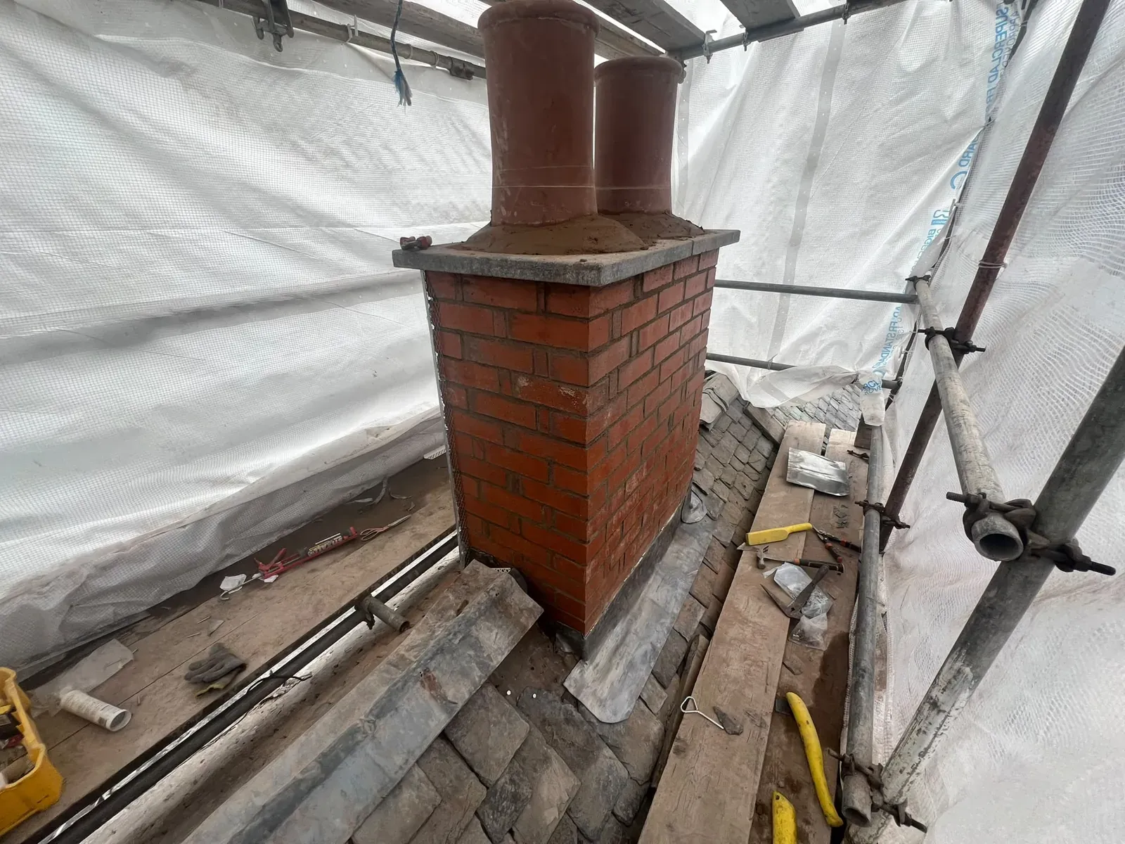 Rebuilt brick chimney stack with clay pots refitted