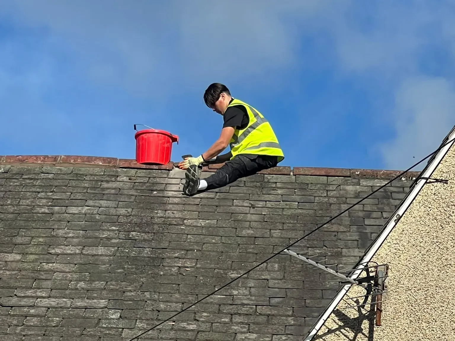 Roofer working along the ridge of a slate roof on a semi-detached house