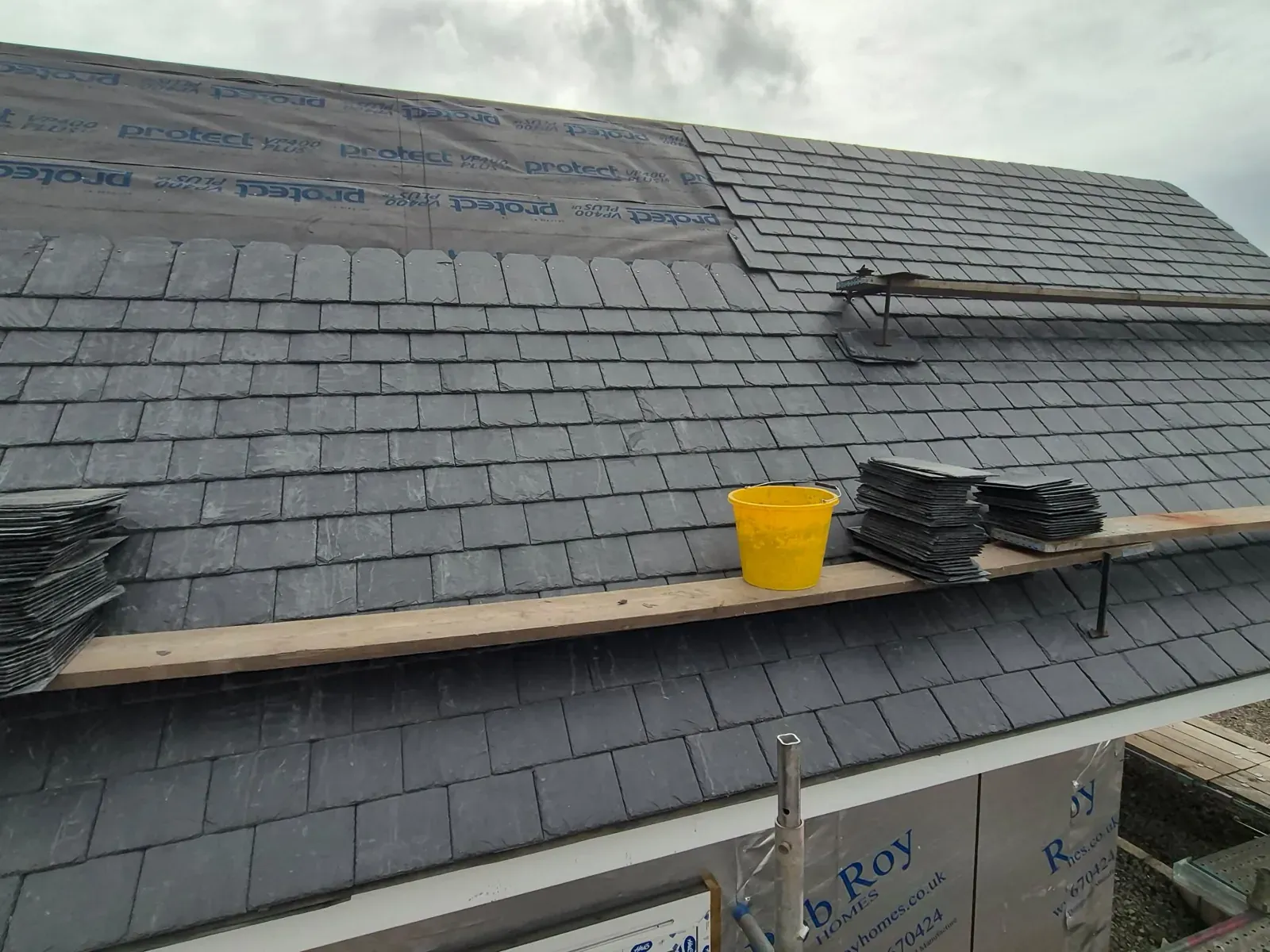 Natural slates being laid over breathable roofing membrane on a new roof